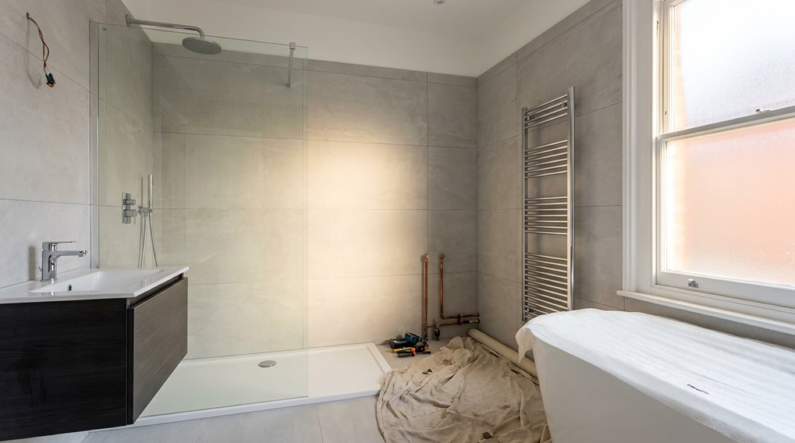 An illustrative renovated bathroom with a walk-in shower, vanity unit and tiled walls