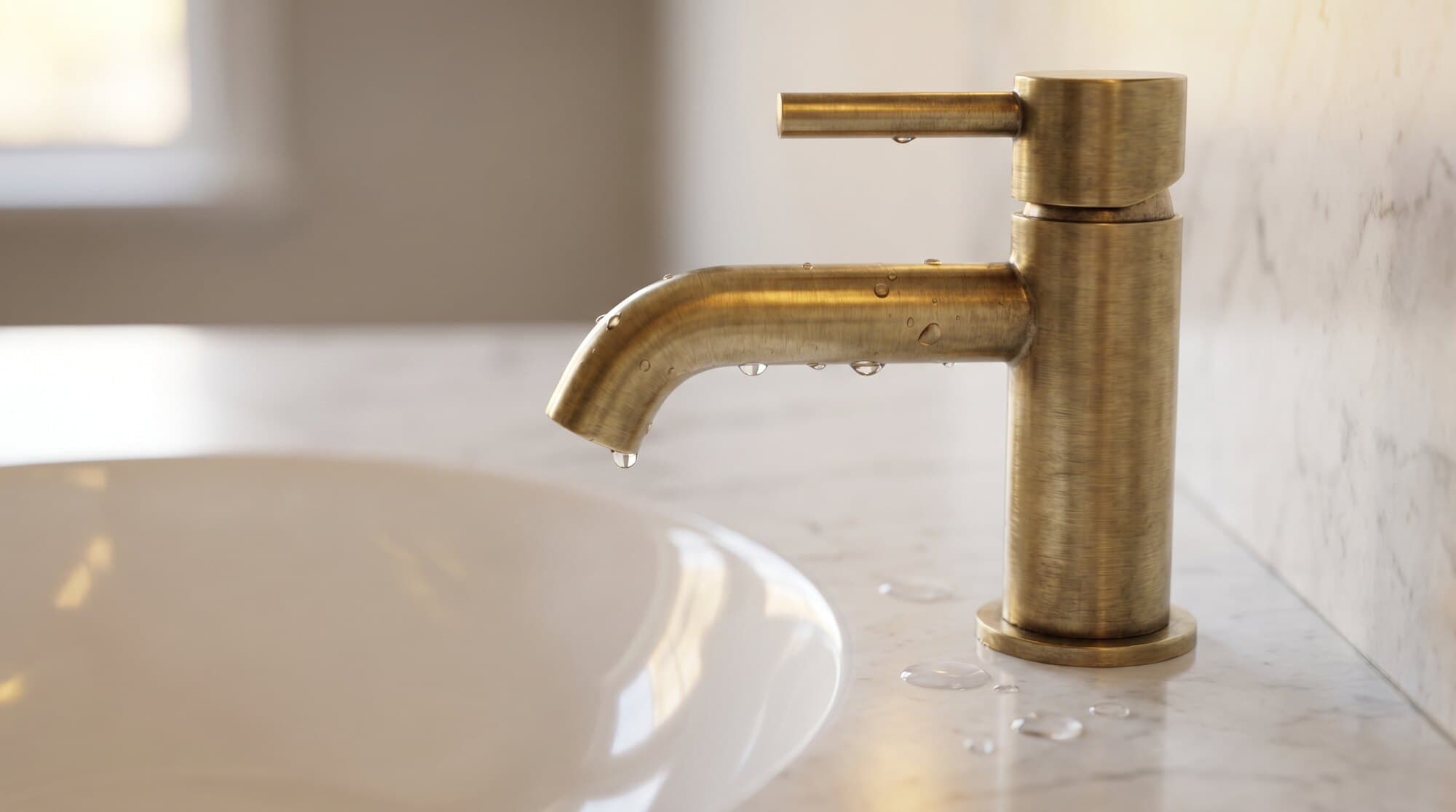 Close-up of a brushed-brass mixer tap against a marble surface.