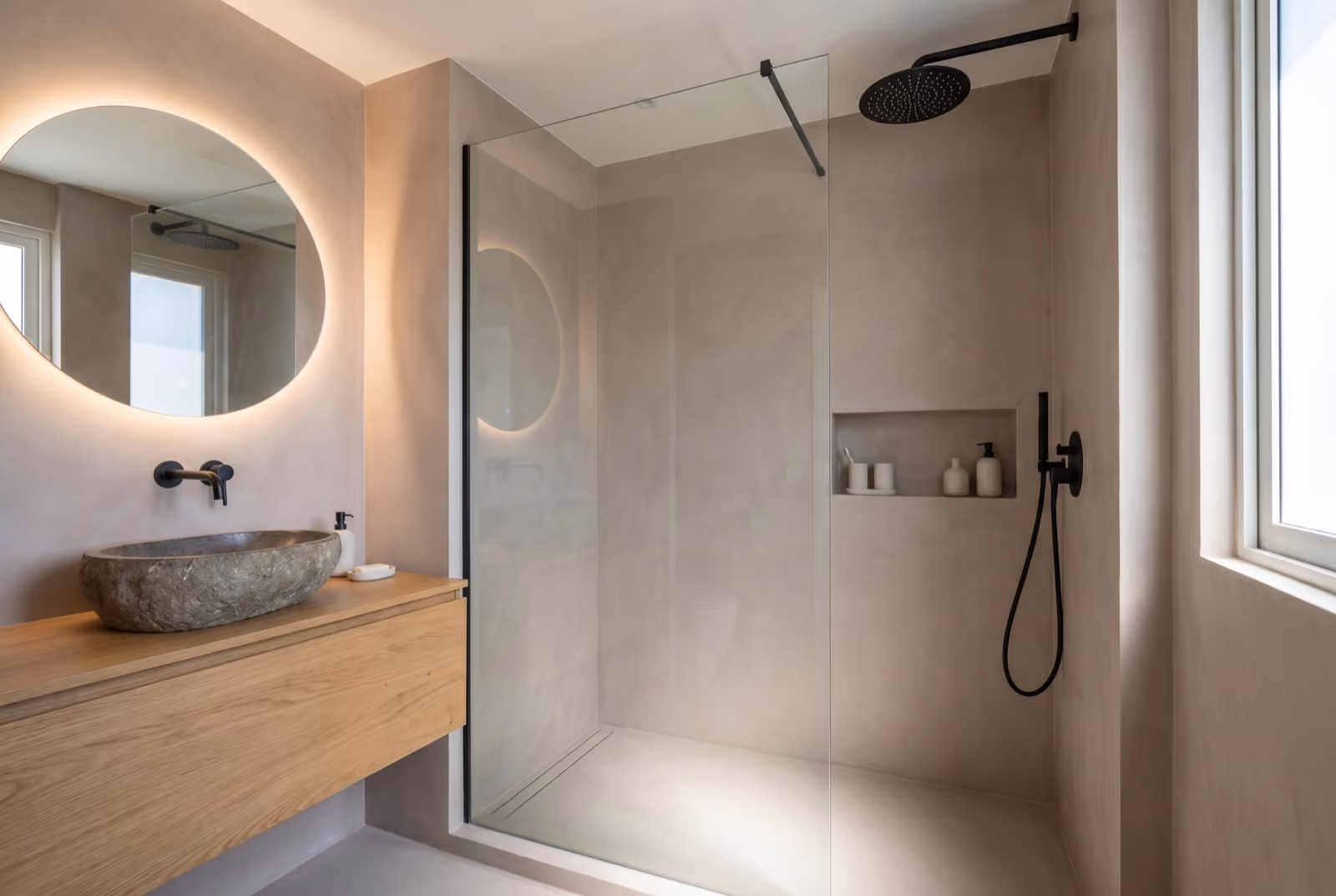 A finished ensuite shower room with a walk-in glass shower, microcement walls and an oak vanity.
